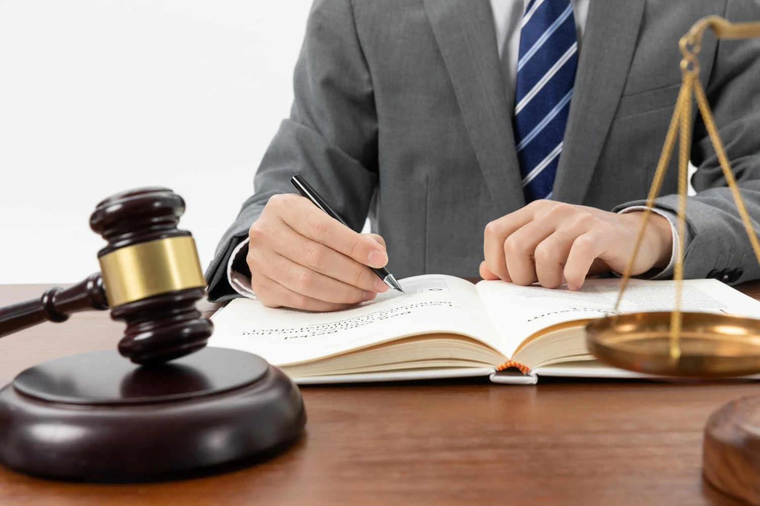 A lawyer sitting behind a desk writing in a book with a gavel on the table